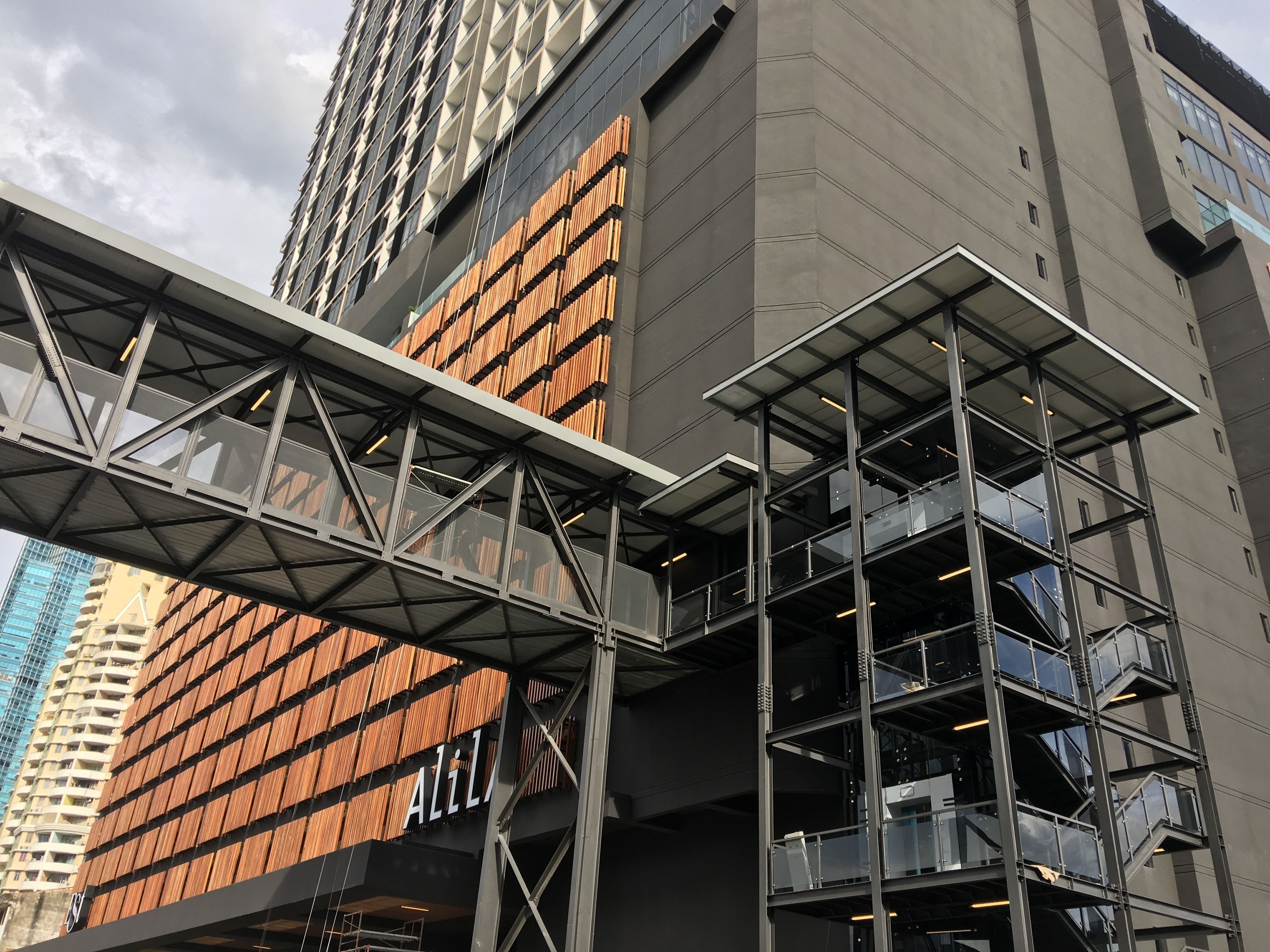 Un edifici modern amb un cartell prominent d'ALI, una estructura de pont metàl·lica i un disseny de diversos pisos.
