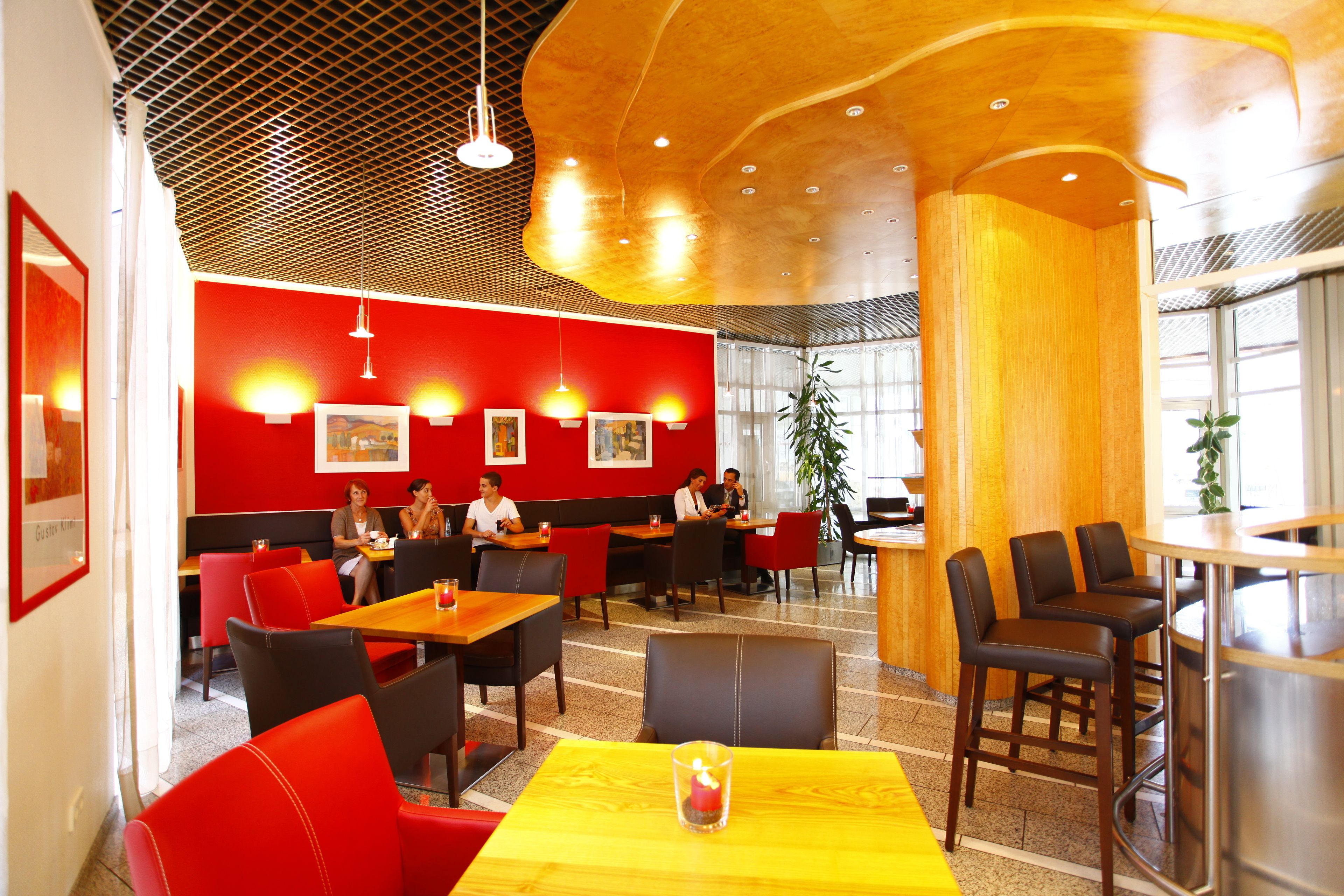 A restaurant with red walls, wooden ceiling, and multiple seating areas including booths and tables.