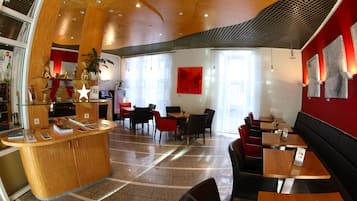 A modern interior with a reception desk, seating area, and large windows allowing natural light.