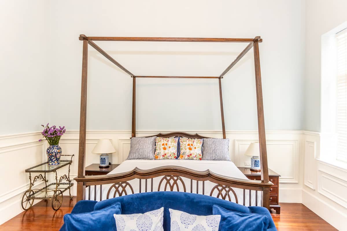 A four-poster bed with a wooden frame and a blue upholstered headboard.