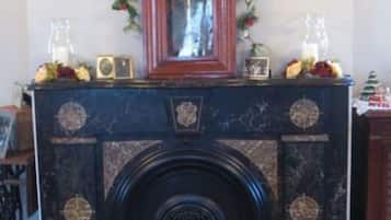 Una chimenea rodeada de objetos decorativos y un tapete floral, con un reloj encima.