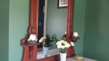 A wooden dresser with a marble countertop and a mirror above it. There are two potted plants on the countertop.