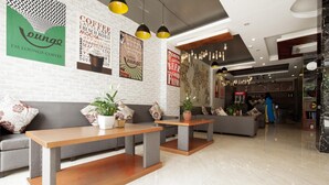 A modern lounge area with seating and tables, a coffee machine, and a menu board. - Ha Long Seoul Hotel (Bai Chay)