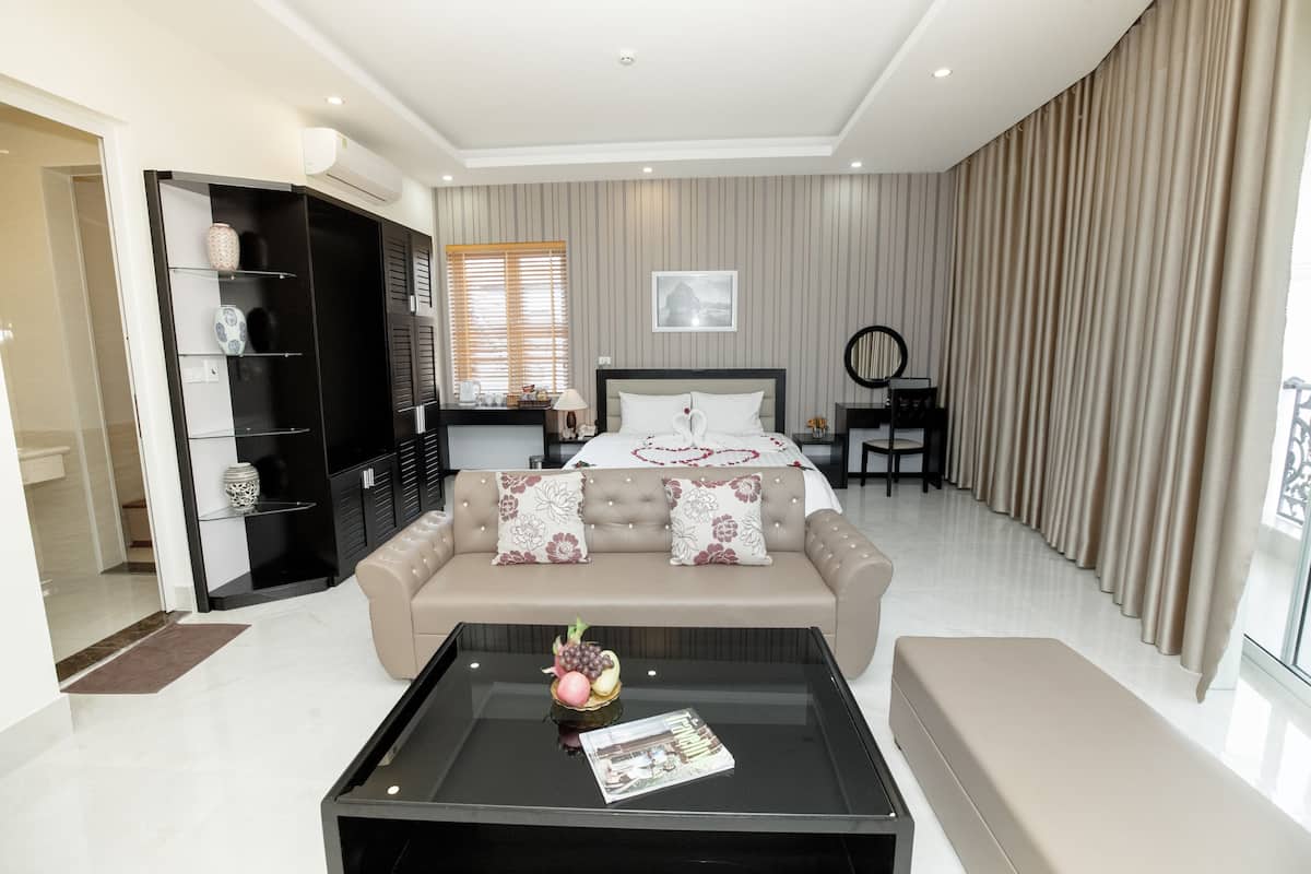 A modern hotel room with a bed, a sofa, a coffee table, a TV, and a wardrobe.