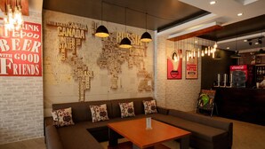 A cozy seating area with a sofa and a table, a wall with a world map design, and a bar area with a Coca-Cola sign. - Ha Long Seoul Hotel (Bai Chay)