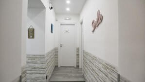 Un pasillo estrecho con piso de madera y una puerta blanca al final.
