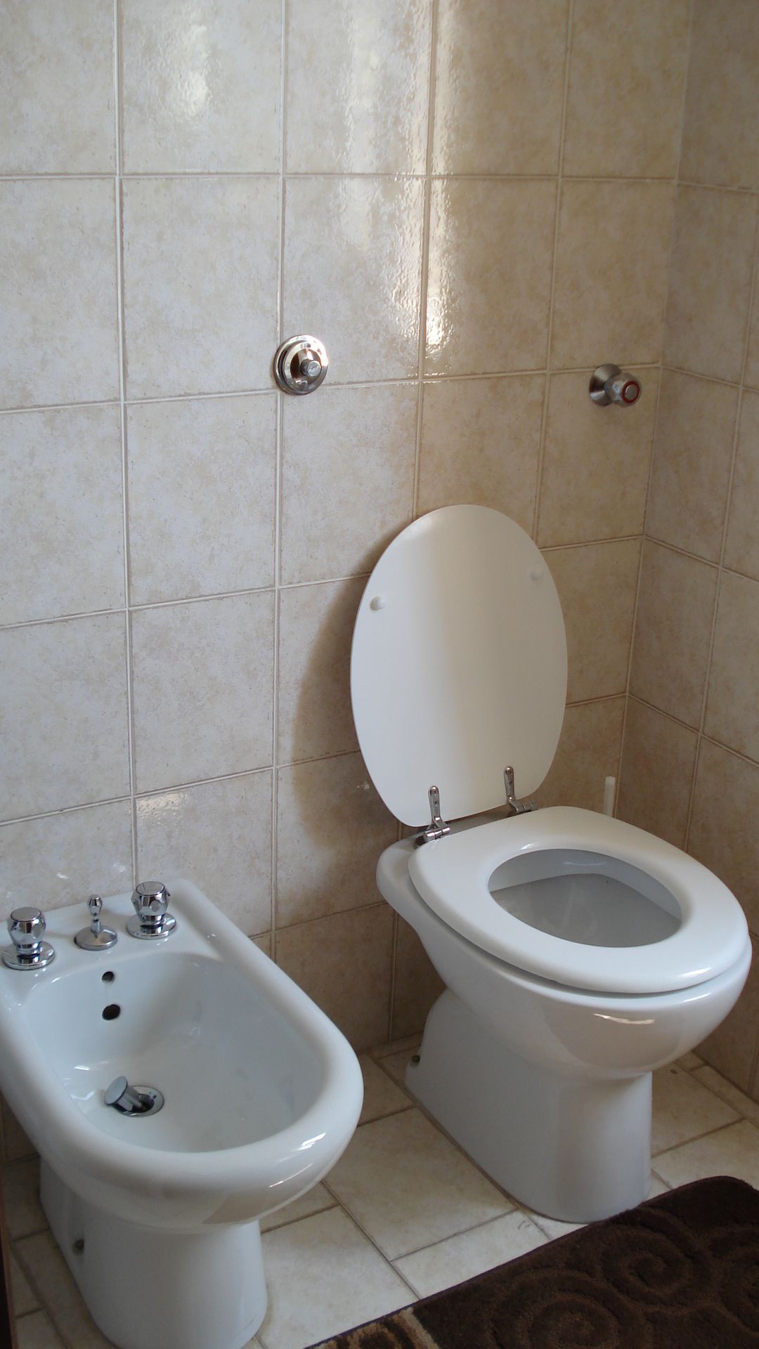 Een badkamer met een bidet, toilet en wastafel.