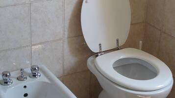 Een badkamer met een bidet, toilet en wastafel.