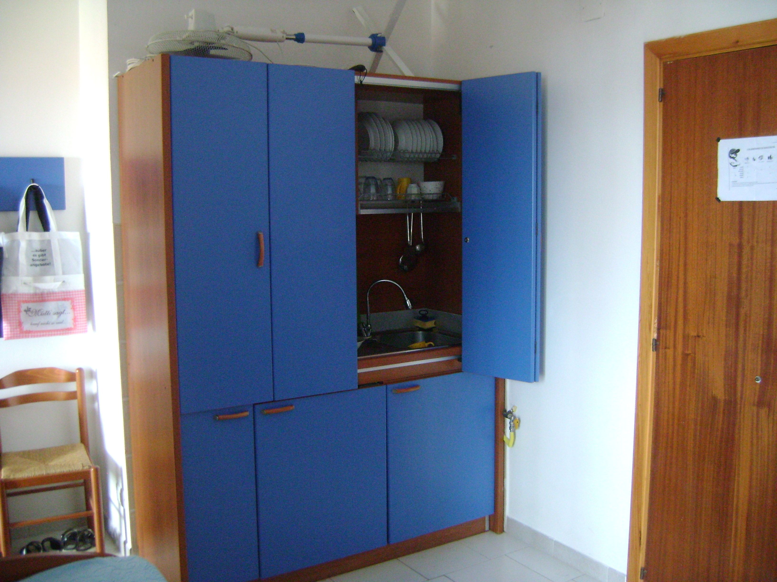 Een blauwe kast met een kleine keukenhoek, inclusief een spoelbak en bestek.