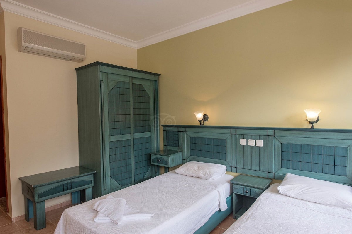 Una habitación de hotel con dos camas, un armario y un escritorio.