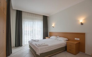 A hotel room with a bed, bedside tables, a nightstand, a lamp, and a window with curtains. - Celay Hotel (Fethiye)