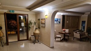 Vestíbulo de hotel con mostrador de recepción, zona de estar y puerta que da a un estacionamiento.