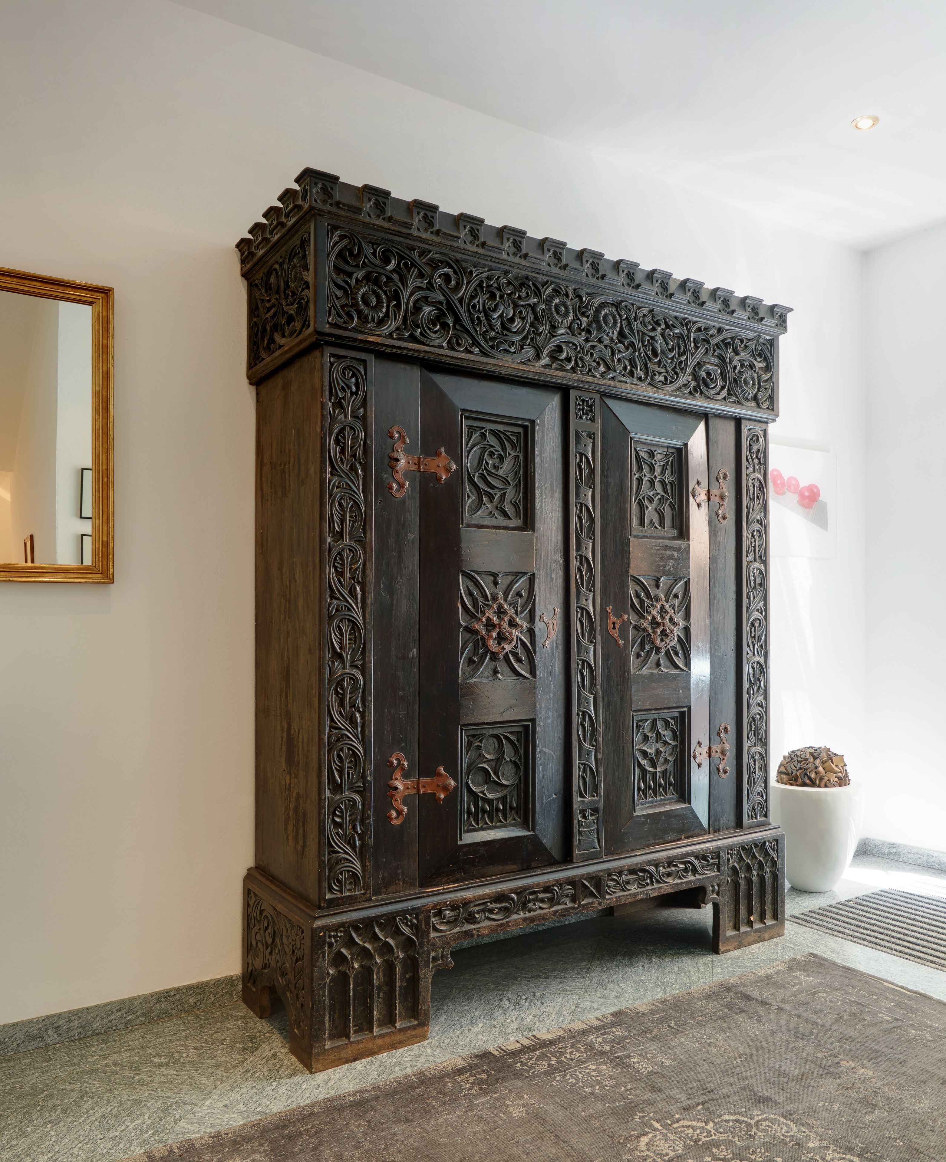 Un mueble de madera oscura con intrincados grabados y un espejo grande a la izquierda.