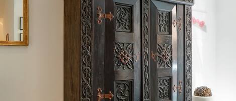 A dark wooden cabinet with intricate carvings and a large mirror on the left.