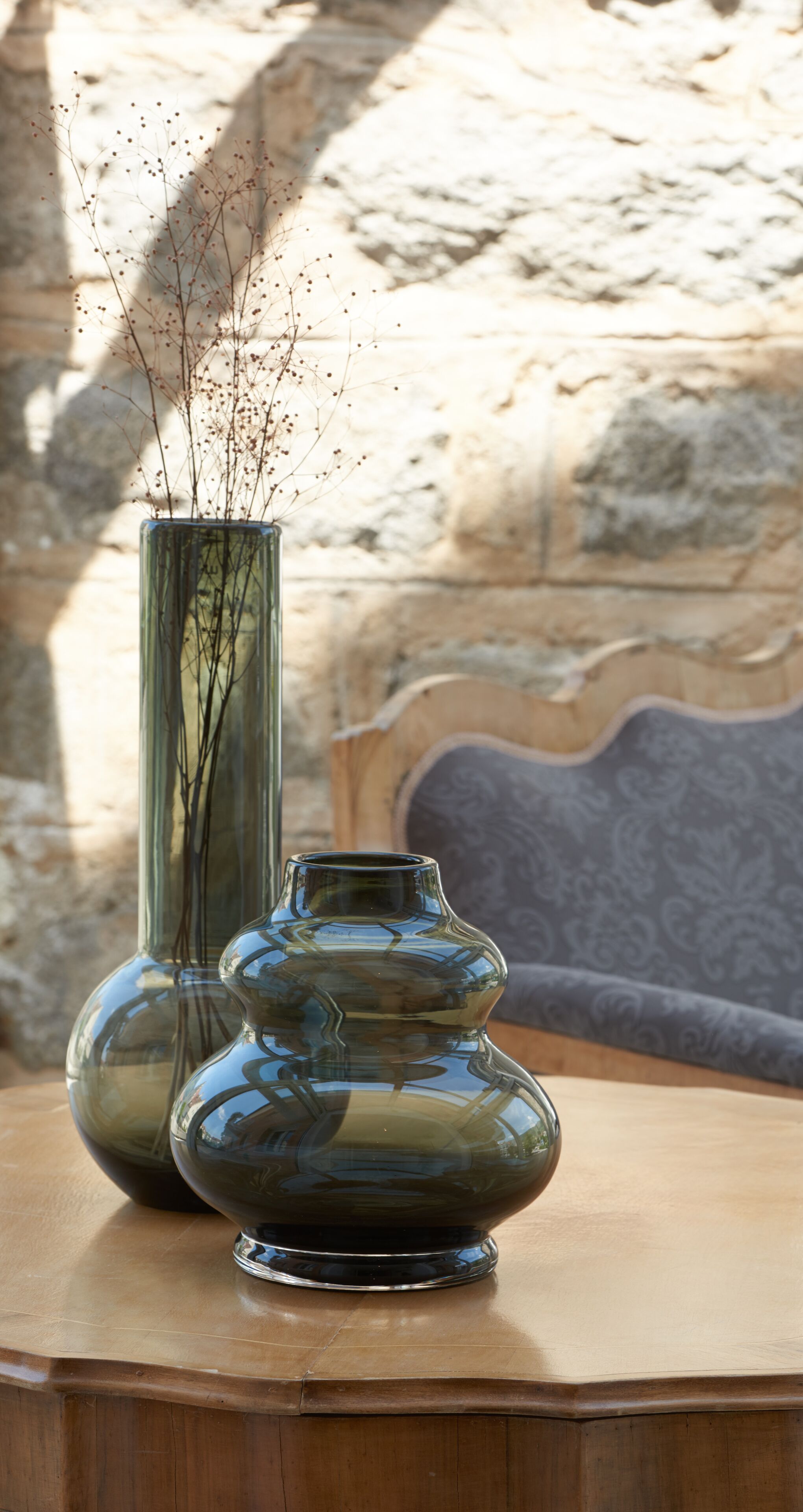 Two glass vases with branches on a wooden table.