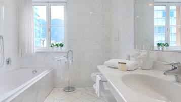 Een moderne badkamer met een bad, een groot wastafel en een toilet. Er staan planten op de vensterbank en er is een handdoekhouder.