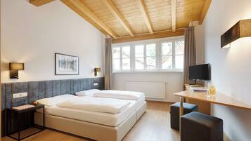 A modern hotel room with a wooden ceiling, a large bed, a desk with a TV, and a window with curtains.
