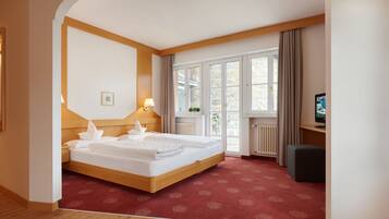 Une chambre d’hôtel avec un lit double, un bureau avec un ordinateur, une fenêtre avec des rideaux et un radiateur.