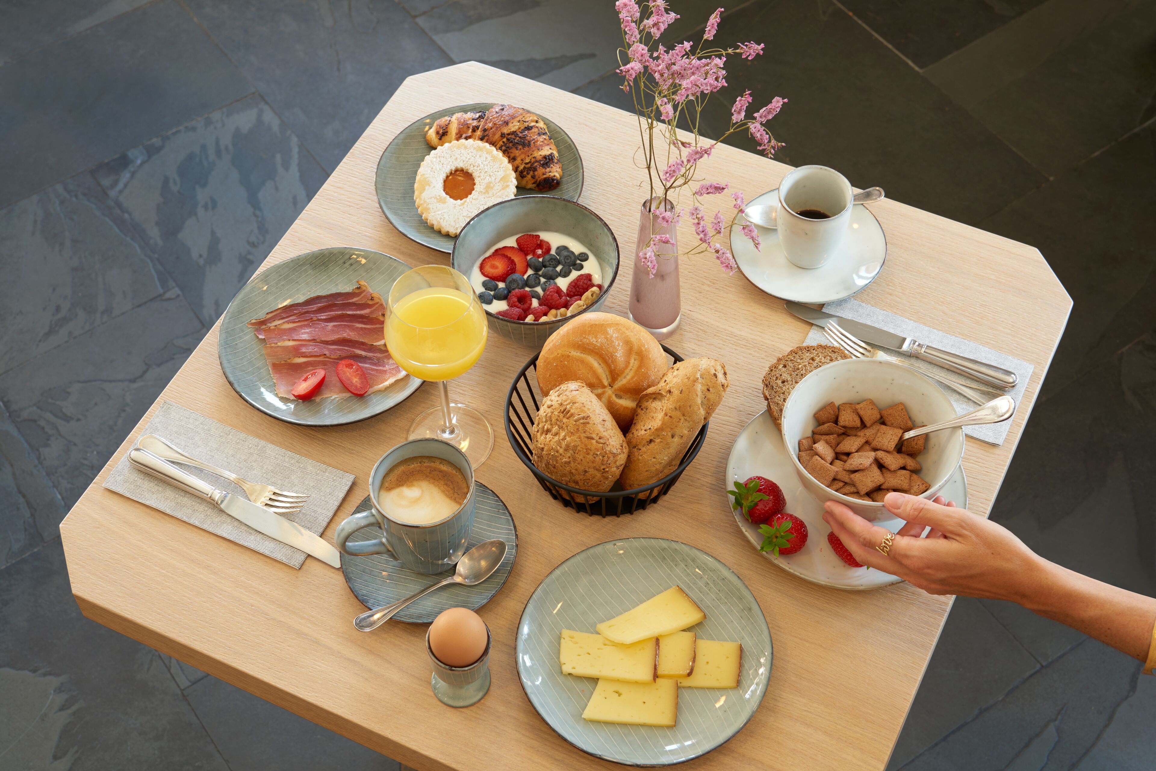 Una tavola imbandita con piatti di cibo, un vaso di fiori e una tazza di caffè.