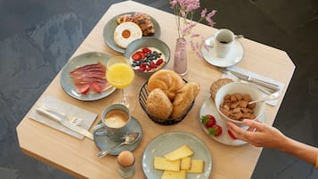 Ett frukostbord med tallrikar fyllda med mat, en vas med blommor och en kopp kaffe.