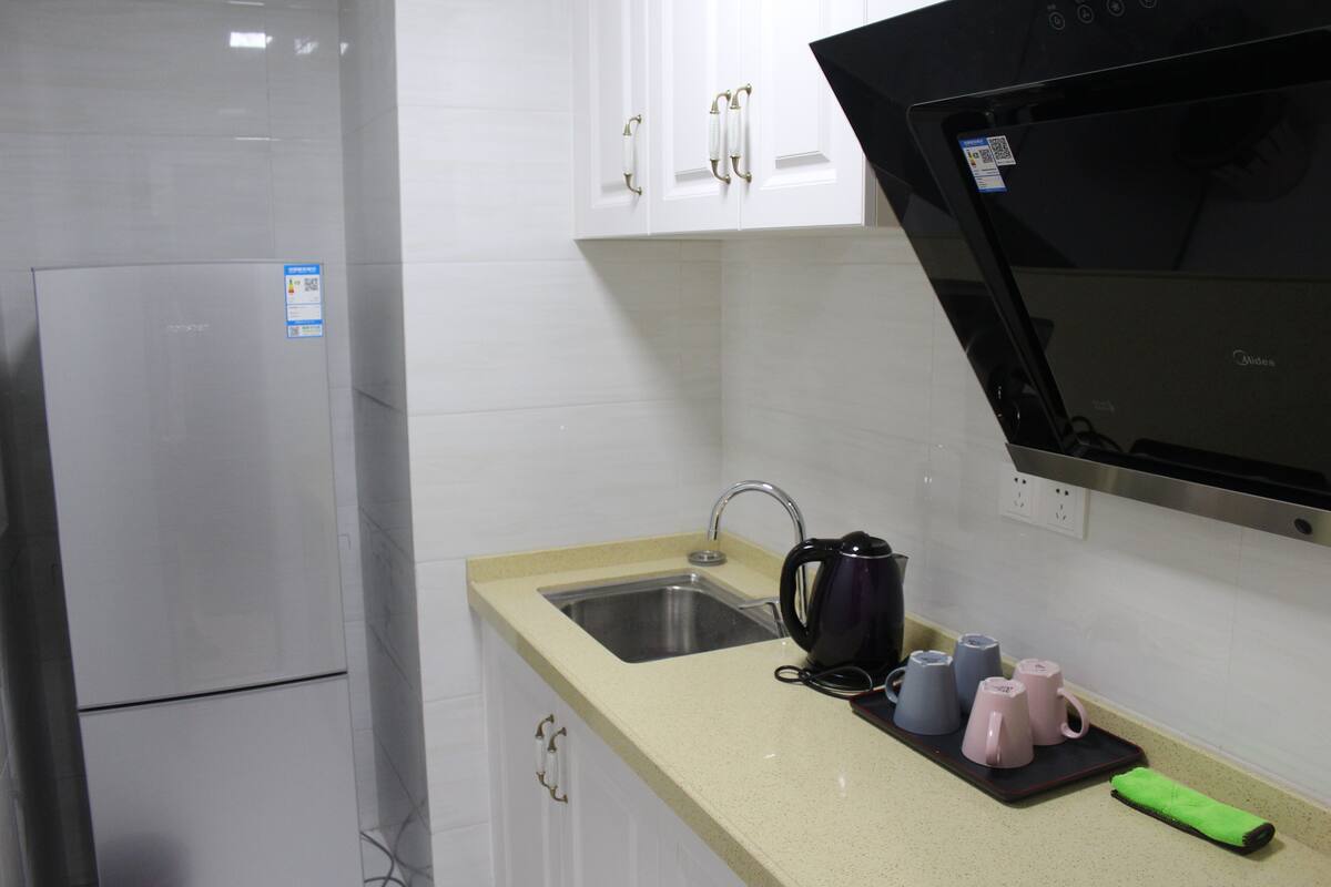 A kitchen with a stainless steel refrigerator, a sink, a microwave, and a coffee maker on the counter.