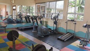 A gym with exercise equipment, colorful mats, and large windows. - Kivu Resort - Hostel (Nakuru)