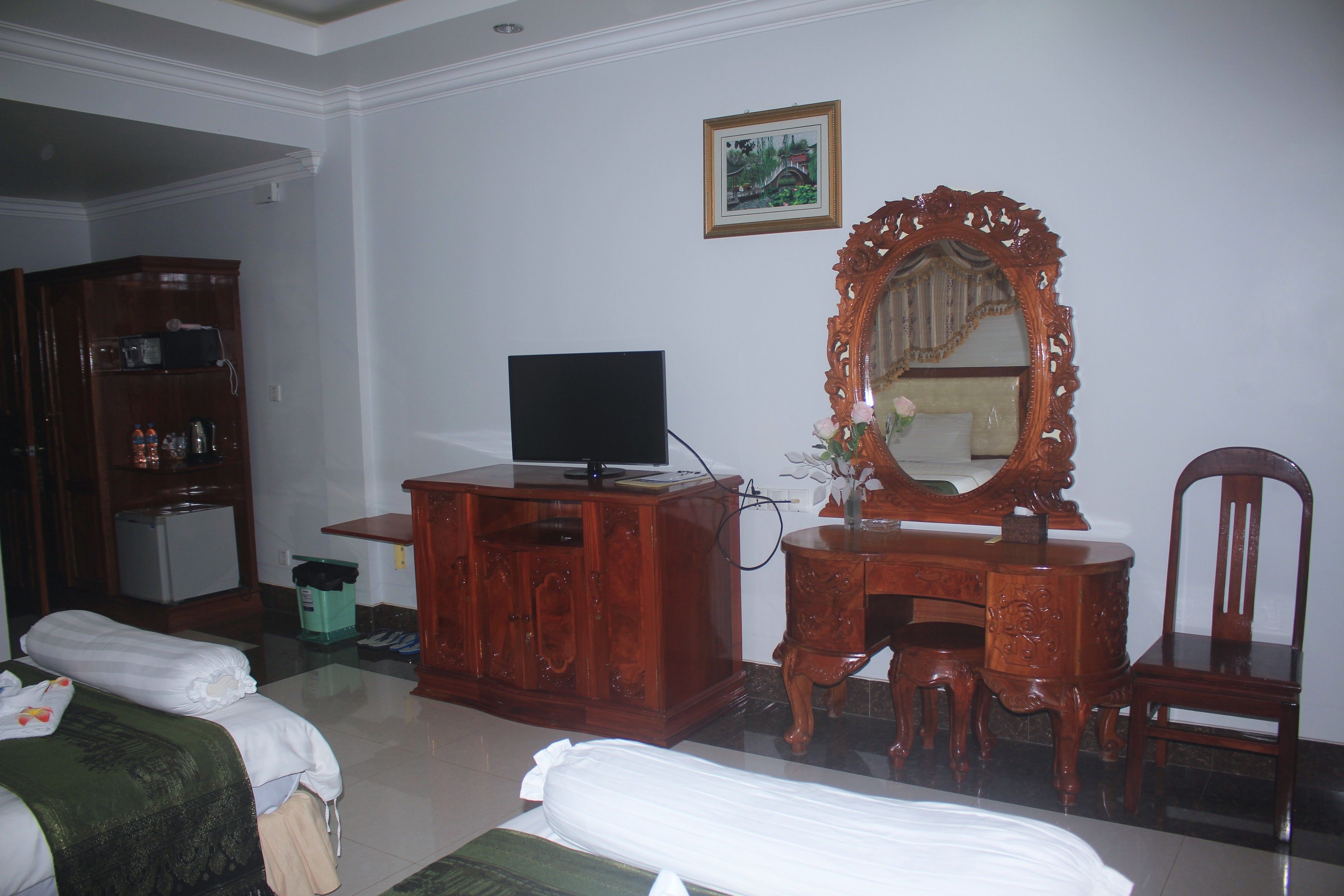 A hotel room with a bed, a wooden dresser with a television, a mirror, and a chair.
