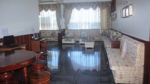 A spacious living room with a round wooden table, a sofa, and a television. - Monorom 2 VIP Hotel (Kampong Cham)