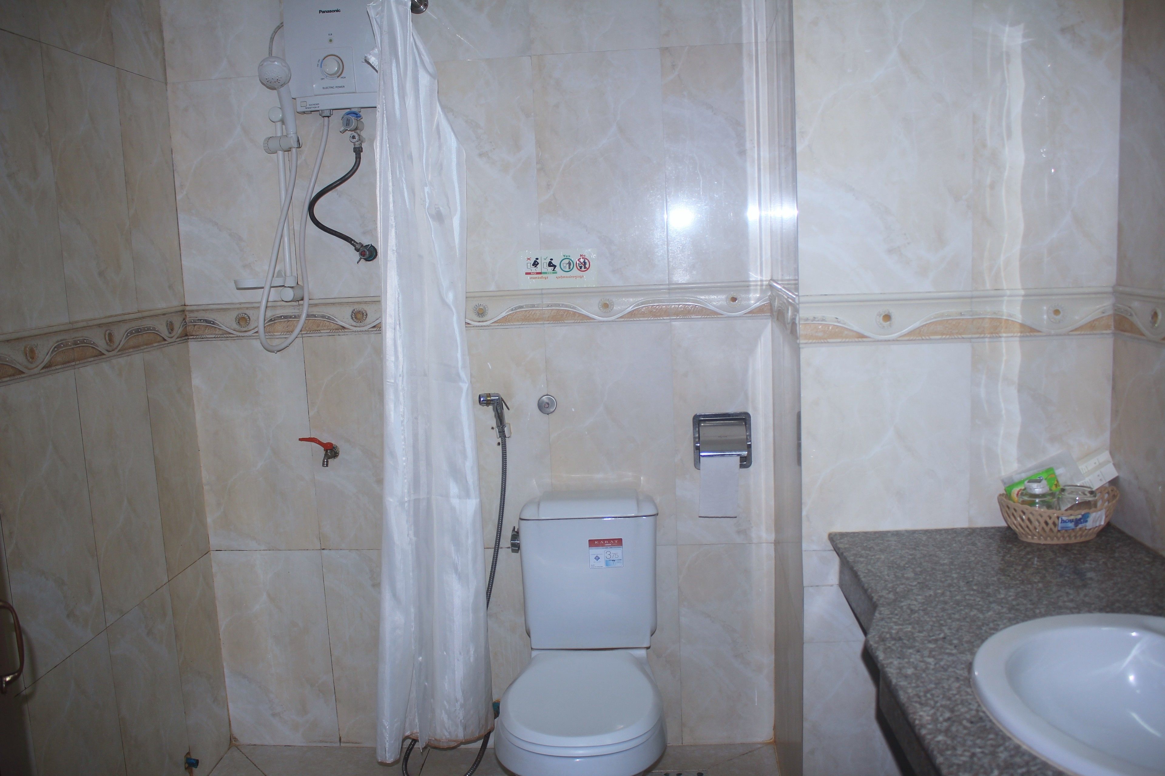 A bathroom with a toilet, shower, and sink.