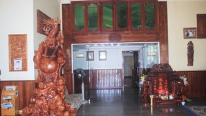 A lobby with a wooden statue, a reception desk, and a large mirror above the door. - Monorom 2 VIP Hotel (Kampong Cham)
