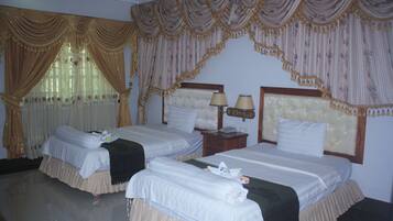 Une chambre d’hôtel avec deux lits, chacun doté d’une tête de lit, d’une table de chevet avec des lampes et d’une fenêtre avec des rideaux.