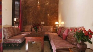 A cozy living room with a sofa set, a coffee table, and a vase of flowers. - Riad Todra (Marrakech)