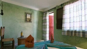 A room with a bed, a chair, a small table, and a window with curtains. - Riad Todra (Marrakech)