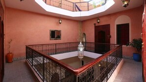 A spacious interior with a high ceiling, a central glass table, and a balcony with a wrought iron railing. - Riad Todra (Marrakech)