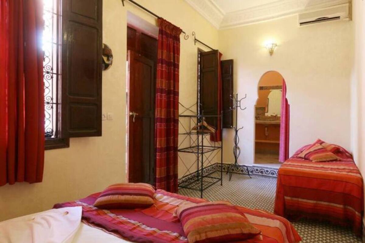 A room with two beds, a wardrobe, a mirror, and a window with curtains.
