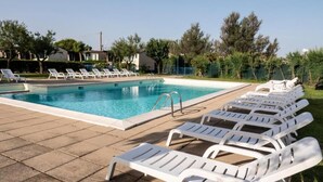 Una piscina con lettini e cielo sereno.