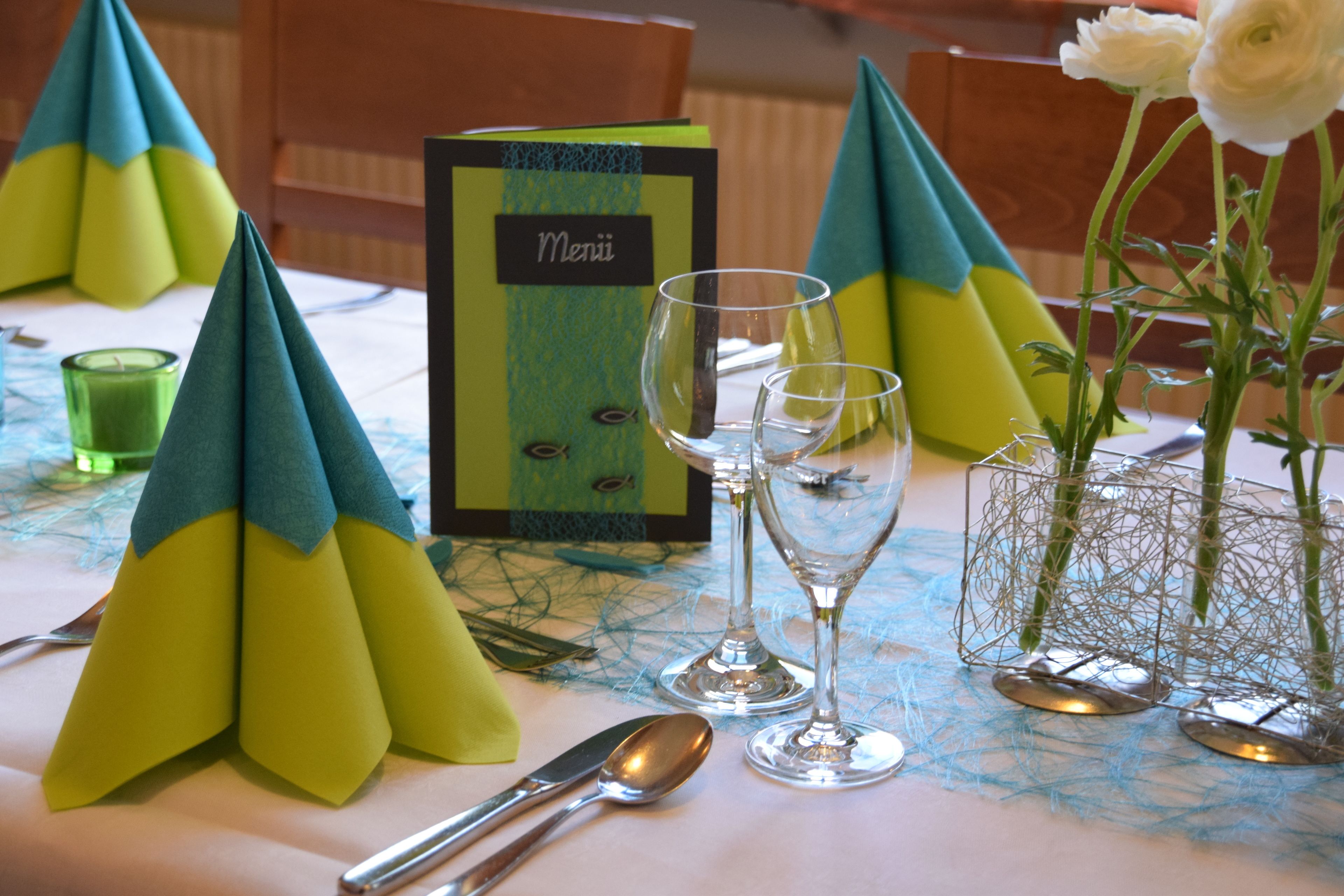 A table set with a menu, glasses, and a vase with flowers.