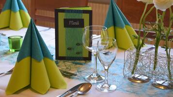 A table set with a menu, glasses, and a vase with flowers.