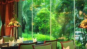 Un restaurante con mesas dispuestas para comer, sillas y vistas a zonas verdes.