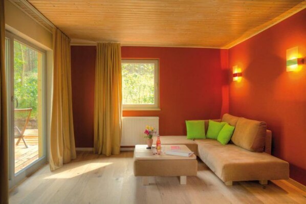 A cozy living room with a sofa, ottoman, and a window with curtains.