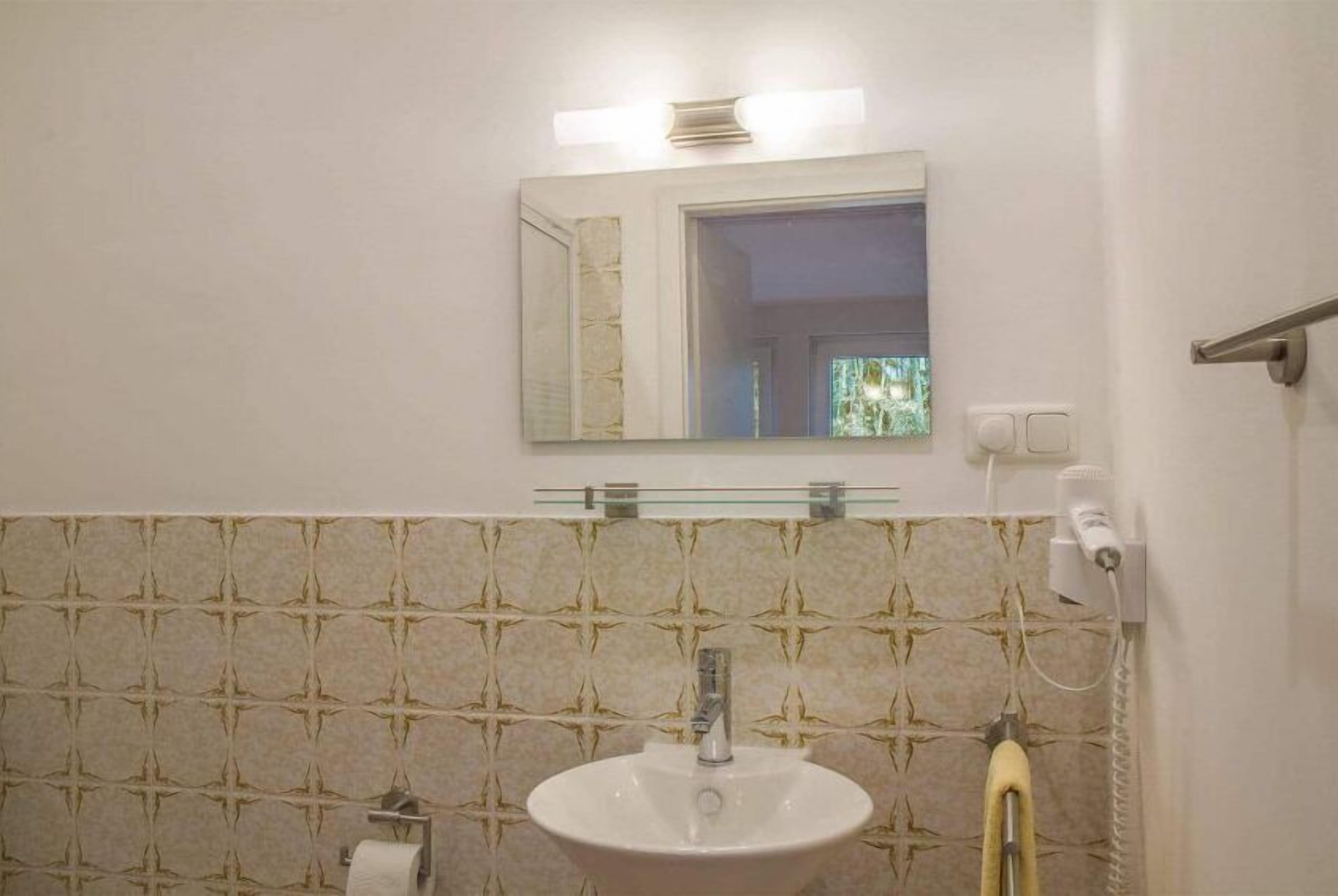 A bathroom with a white sink, a mirror, and a towel rack.