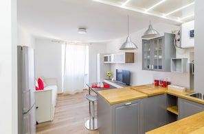 A modern kitchen with a wooden countertop, grey cabinets, and a built-in microwave.