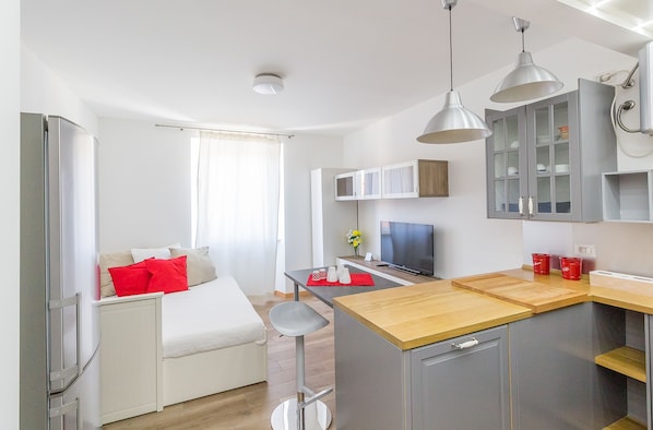 A modern kitchen with a wooden countertop, grey cabinets, and a built-in TV.