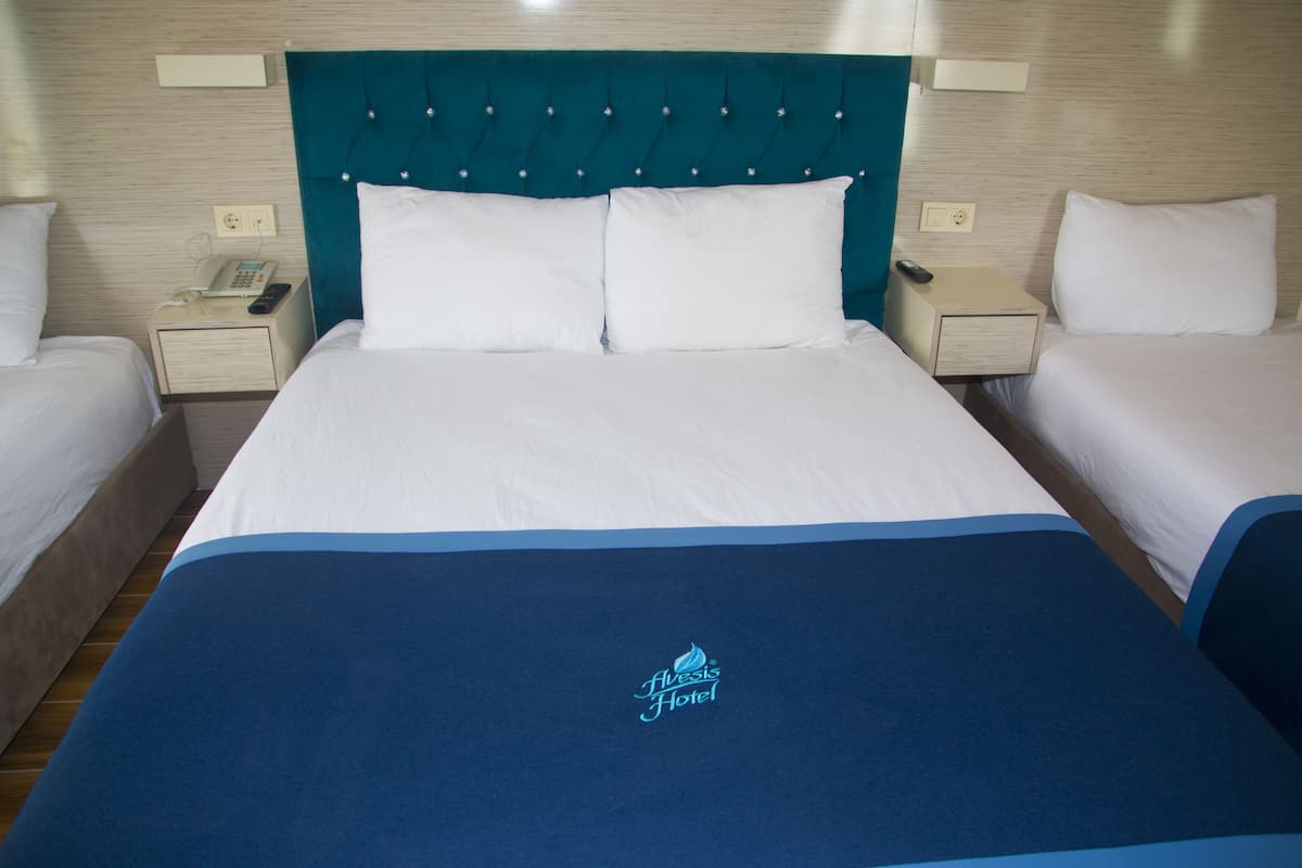 A hotel room with a large bed, two bedside tables, a telephone, and a remote control.
