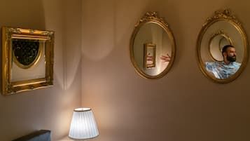 Et værelse med to dekorative, gyldne spejle på væggen, en moderne lampe og en mørk stol.