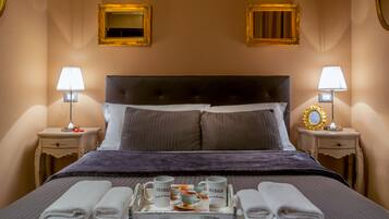 A neatly made bed with a tray of breakfast items, two bedside lamps, and framed mirrors on the walls.