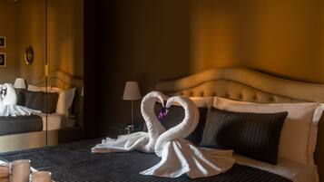 A hotel room with a bed, pillows, a bedside table with a lamp, and a mirror.