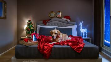 A bedroom with a dog on the bed, a Christmas tree, and holiday decorations.