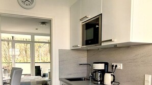 A modern kitchen with a microwave, coffee maker, and a clock on the wall. - Apartment Regina am schönen Möhnesee (Moehnesee)