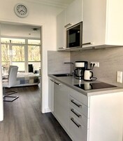 Uma cozinha moderna com micro-ondas, cafeteira e relógio na parede.